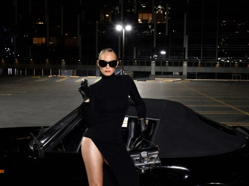 Amber Valletta in a black turtleneck dress posing against a black car at night for System Magazine