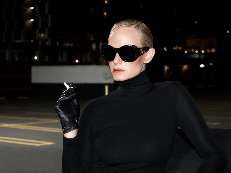 Amber Valletta in sunglasses and black turtleneck holding a cigarette in black leather gloves at night