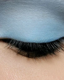 Close-up macro shot of a closed eye with matte blue eyeshadow and dark eyelashes for Tush Magazine editorial