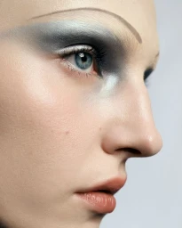 Close-up profile portrait of a woman with dramatic grey eye makeup and thin drawn eyebrows for Tush Magazine.