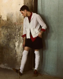 Model Slava Sikorski in white zip jacket and red shirt standing against textured wall for Vanity Teen Magazine