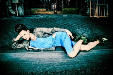 Model lying on pavement wearing a blue dress and patterned jacket for PAP Magazine editorial