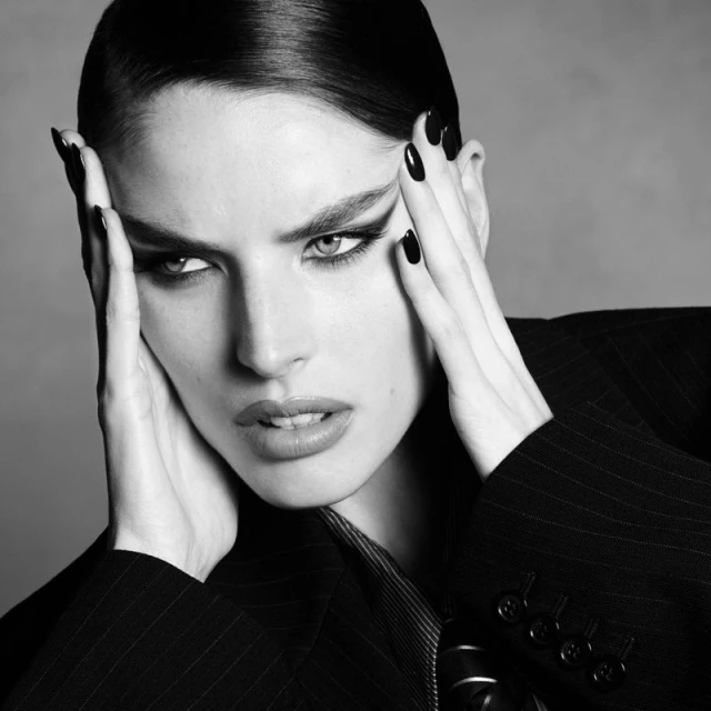 Close-up portrait of model Libby Taverner holding her head with dark manicured hands for Double Vision by Luigi & Iango