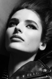Close-up monochrome portrait of model Libby Taverner wearing a dark leather jacket with zipped lapel details.