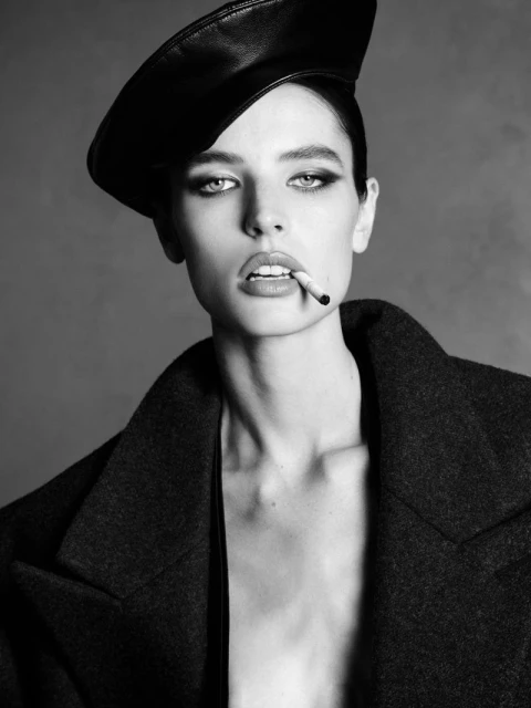 Model Libby Taverner wearing a leather beret and dark coat with a cigarette in her mouth for Double Vision.