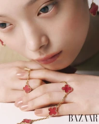 Close-up portrait of a woman wearing gold clover earrings and red floral motif jewelry for Harper's Bazaar Korea Pink Fortune