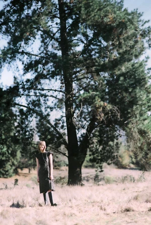 Model standing in a grassy woodland field beneath a tall pine tree for L'Officiel Chile