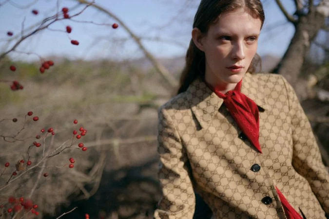 Model in patterned jacket and red scarf outdoors near bare branches with red berries for L'Officiel Chile