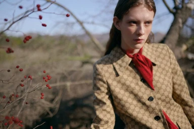 Model in patterned jacket and red scarf outdoors near bare branches with red berries for L'Officiel Chile