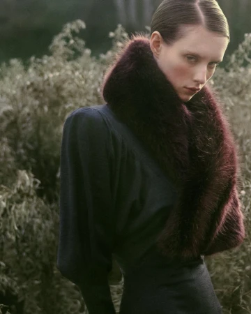 Model in dark top with a rich burgundy faux fur collar outdoors against a leafy background for Forest Memories editorial