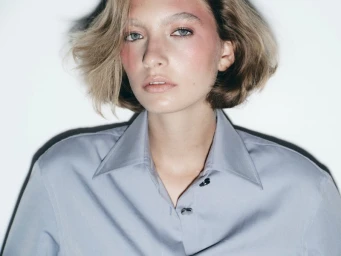 Model with blonde bob wearing a light blue button-up shirt against a plain white background for Harper's Bazaar Espana.