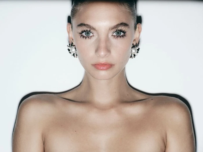 Close-up portrait of a model with statement pearl earrings against a white background for Harper's Bazaar España