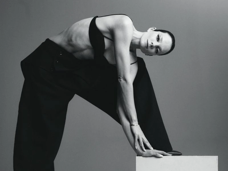 Model Eniko Mihalik posing in a black top and trousers against a neutral grey studio background for Forbes Spain.