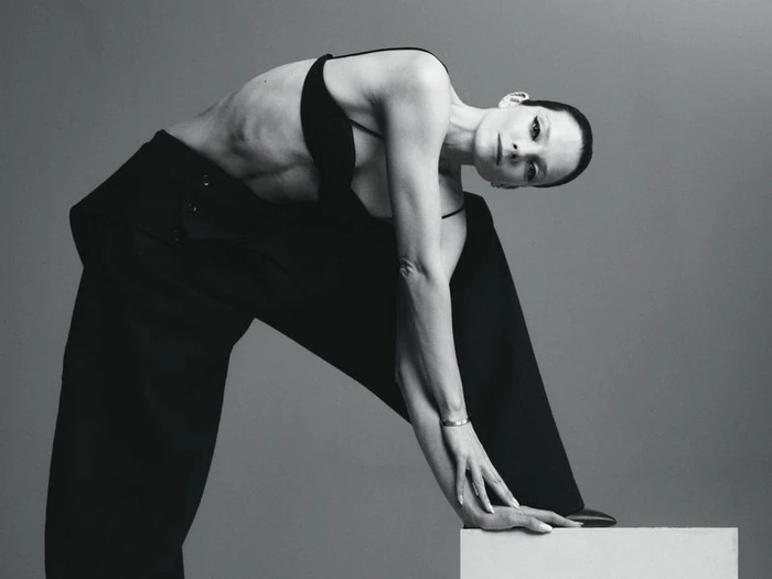 Model Eniko Mihalik posing in a black top and trousers against a neutral grey studio background for Forbes Spain.