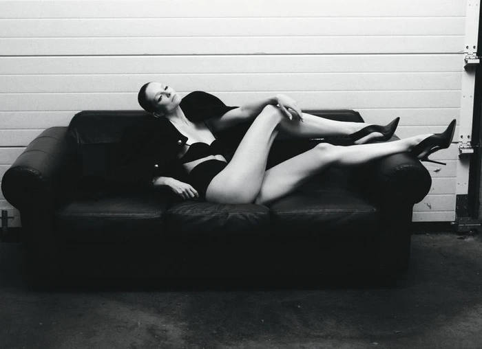 Eniko Mihalik reclining on a dark leather sofa in black lingerie and stilettos for Forbes Spain by Javier Biosca.