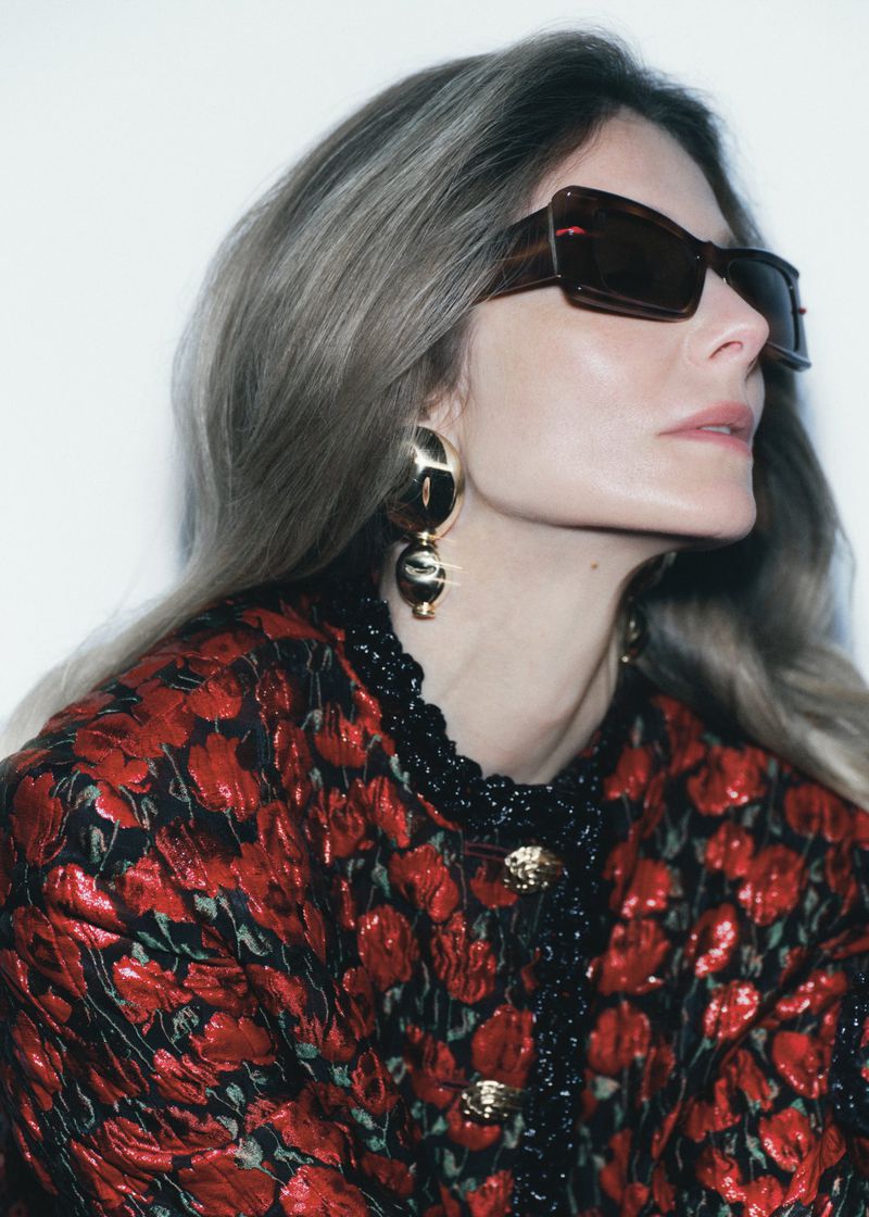 Eniko Mihalik wearing dark sunglasses and a red patterned jacket against a white background for Forbes Spain editorial