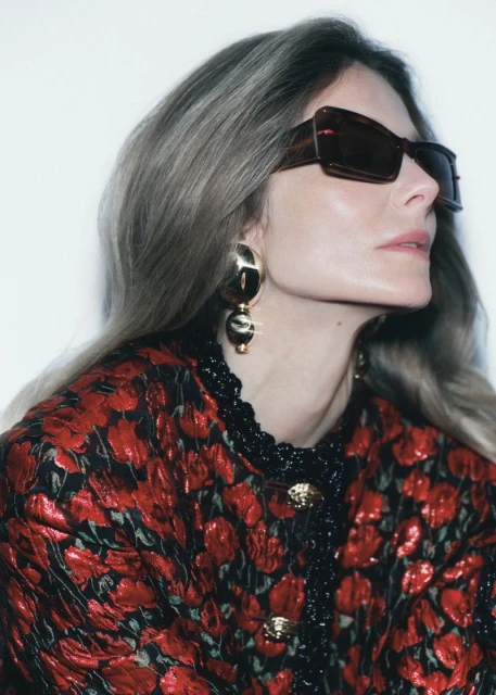 Eniko Mihalik wearing dark sunglasses and a red patterned jacket against a white background for Forbes Spain editorial