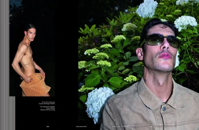 Man wearing sunglasses and a beige jacket against a lush green hydrangea bush background in an editorial spread.