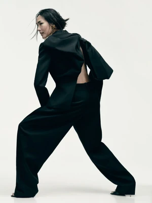 Model in a black suit posing against a white background for Grazia UK
