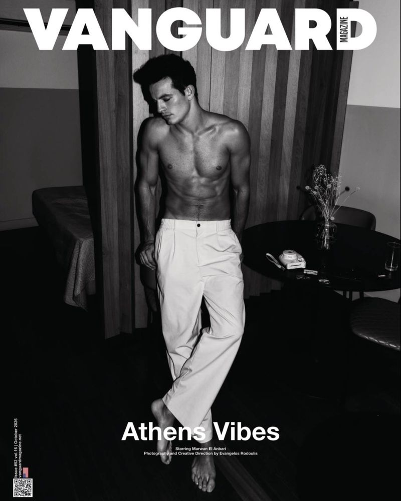 Monochrome magazine cover portrait of a shirtless man wearing light trousers standing indoors