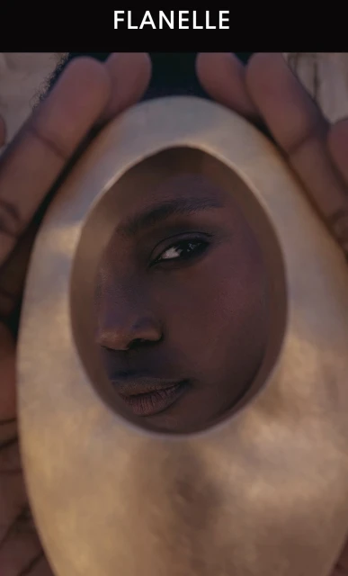 Close-up portrait of a person looking through an oval metallic sculptural frame, photographed by Julia Yatel for Flanelle Magazine.