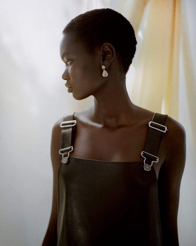 Model Ateta Jok wearing a dark leather dress with silver hardware in a fashion editorial for Puss Puss Magazine by Maya Skelton.