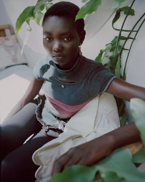 Model Ateta Jok seated indoors surrounded by green foliage for the Silver Rain editorial in Puss Puss Magazine