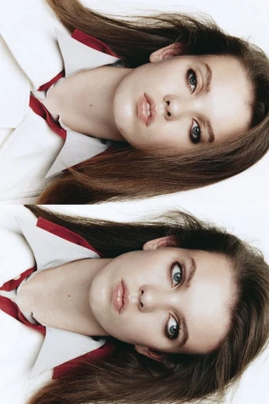 Portrait of a female model wearing a white collared shirt with red trim against a seamless white background.