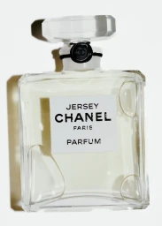 Glass perfume bottle with a faceted stopper and white label against a light background