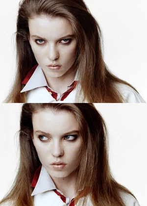 Close-up portrait of a young female model with dark eye makeup wearing a white and red shirt against a white background