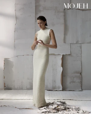 Model in a cream sleeveless dress standing against a textured paper background for Mojeh Magazine