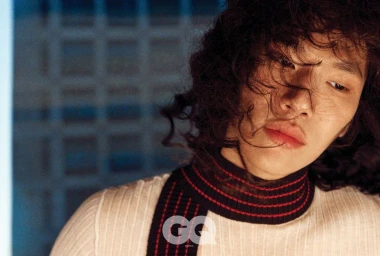 Close-up portrait of model Sanggun Lee with curly hair wearing a white top with red and black stripes for GQ Korea.