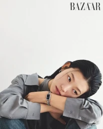 Model resting head on crossed arms wearing a grey shirt and chain-link watch against a white background for Harper's Bazaar Korea