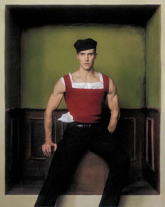 Roberto Bolle in a red knit vest and black trousers wearing a beret