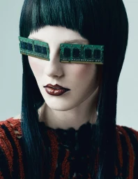 Model with dark hair and RAM sticks over eyes wearing a patterned top against a pale grey background