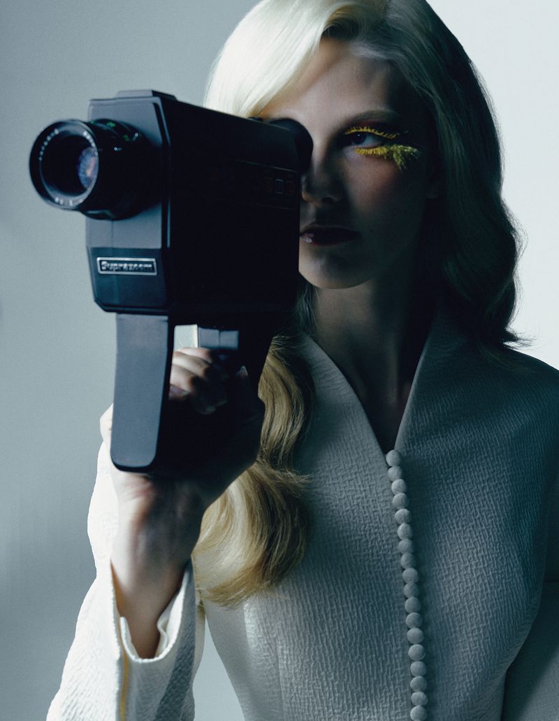 Model Clara Heitkamp holds a vintage Super 8 camera to her eye in a fashion editorial shot by Illya Ovchar for Tush Magazine.