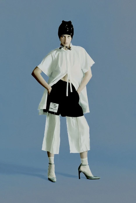 Model Ksenia Lifanova in a white tunic and black shorts against a blue studio background for Vogue Portugal