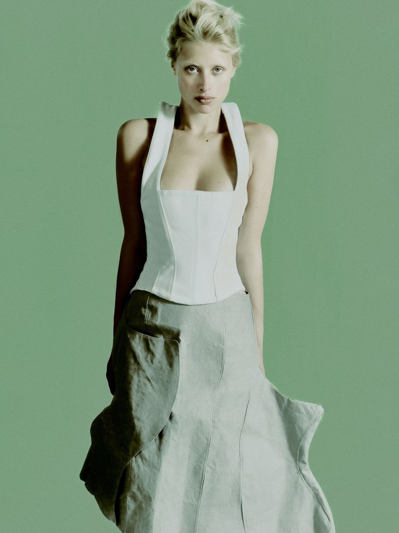 Model Ksenia Lifanova wearing a white halter top and grey skirt against a green background for Vogue Portugal.