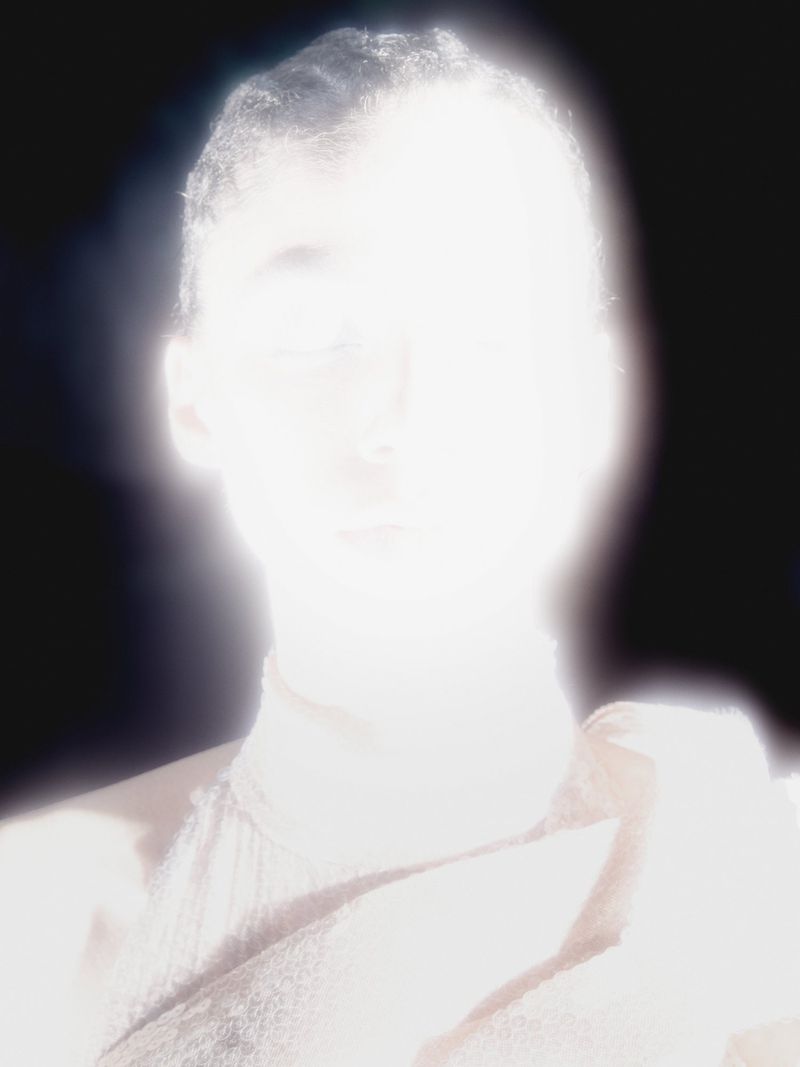 High-key portrait of an adult with a bright overexposed lighting creating a glowing effect, shot with a shallow depth of field.