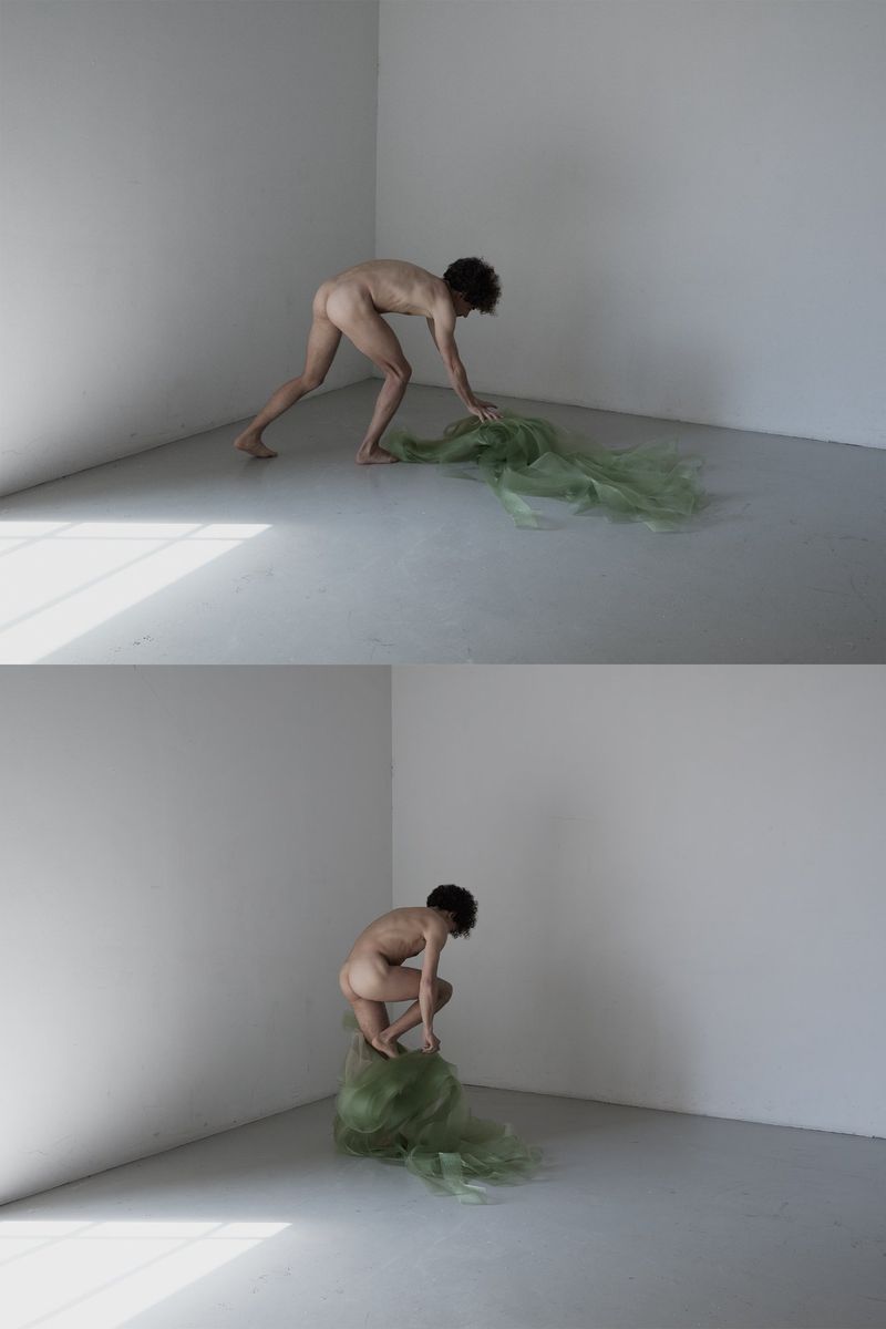 Striking studio art photograph featuring a nude adult and airy green fabric, creating a surreal, minimalist aesthetic in a white corner.