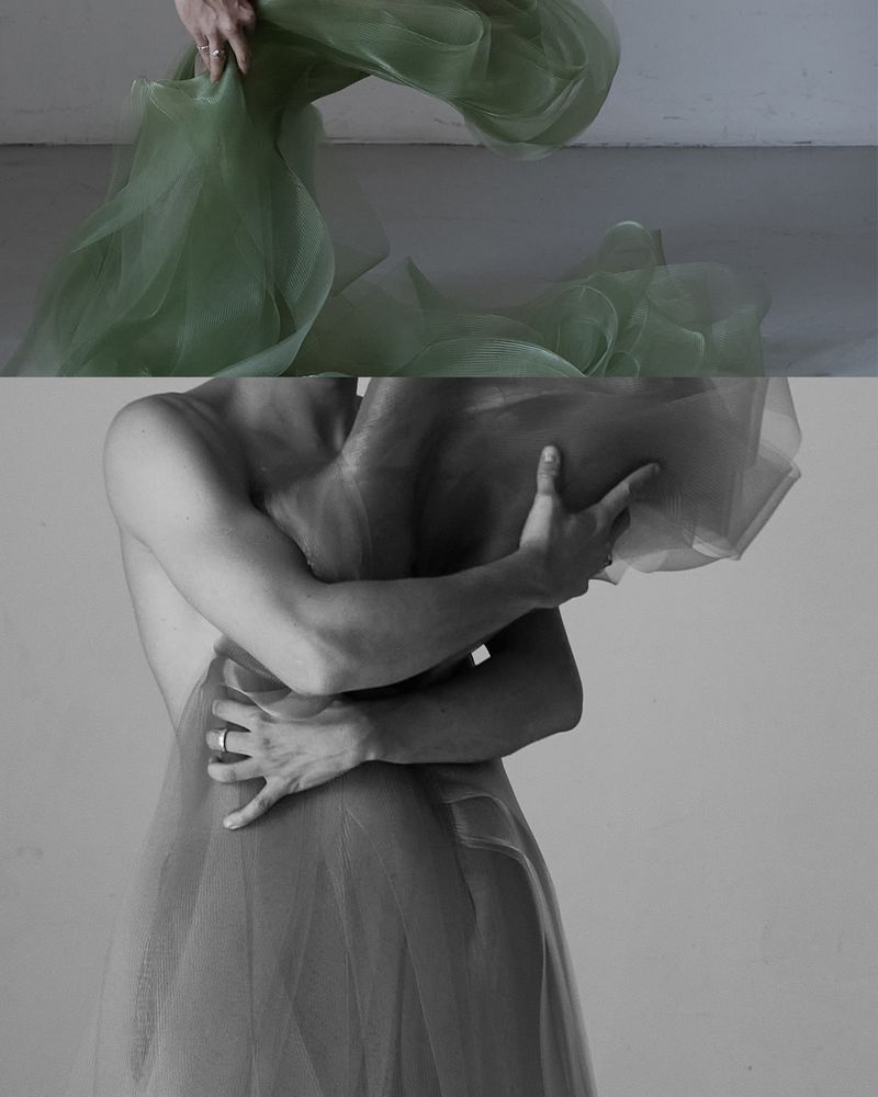 Monochromatic studio shot of person draped with sheer fabric, artfully obscuring form and focusing on texture and light.