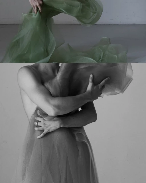 Monochromatic studio shot of person draped with sheer fabric, artfully obscuring form and focusing on texture and light.