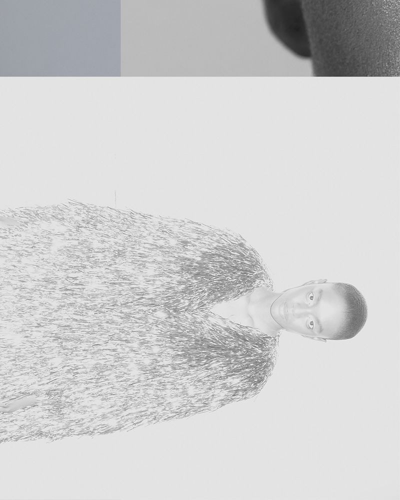 Monochrome portrait of a slender adult model wearing a textured v-neck top, gazing at the camera against a light gradient background.