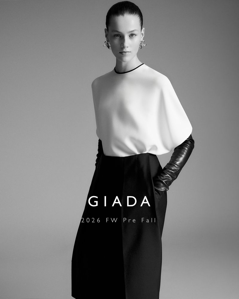 Model Famke van Hasselt in a white top and black skirt with leather gloves against a grey backdrop