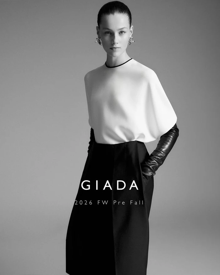 Model Famke van Hasselt in a white top and black skirt with leather gloves against a grey backdrop