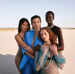 Four models wearing pearl jewellery posing together on a sunny sandy beach for Paspaley Kimberley campaign