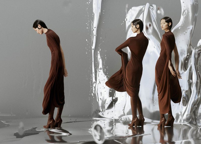 Three fashion models pose in brown dresses and heeled boots against a gray backdrop with reflective silver accents and water textures.