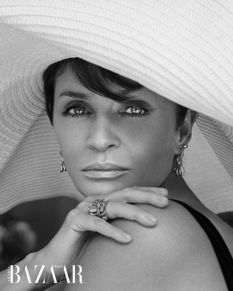 Elegant black and white portrait of a woman in a wide-brimmed hat, featuring detailed jewelry and a sophisticated facial expression.