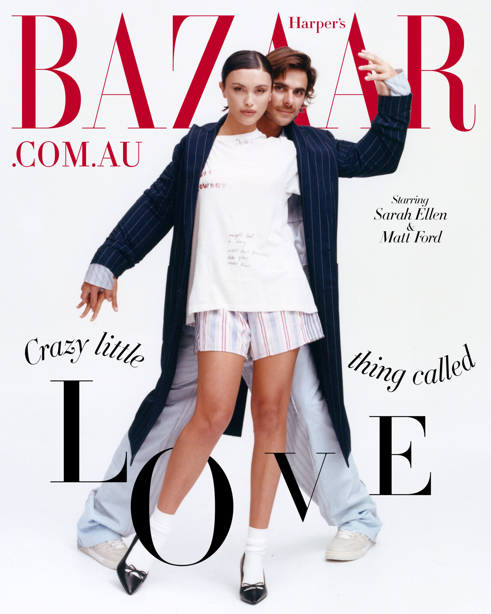 Editorial fashion shot: a woman in shorts stands in front of a man wearing a pinstripe coat, posing on a white background for a magazine cover.