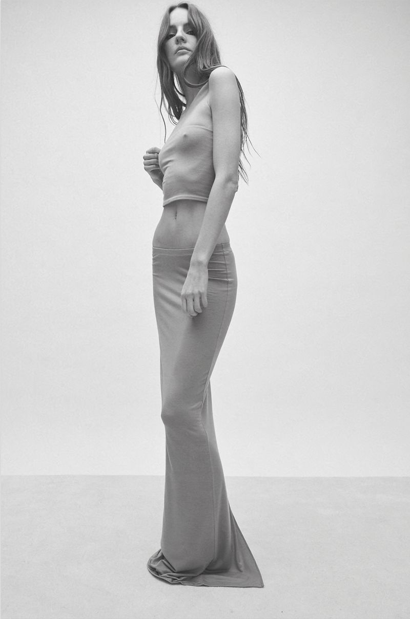 Monochrome portrait of a woman in a sheer top and skirt, minimalist aesthetic, studio lighting, emphasizing fabric texture and subtle pose.